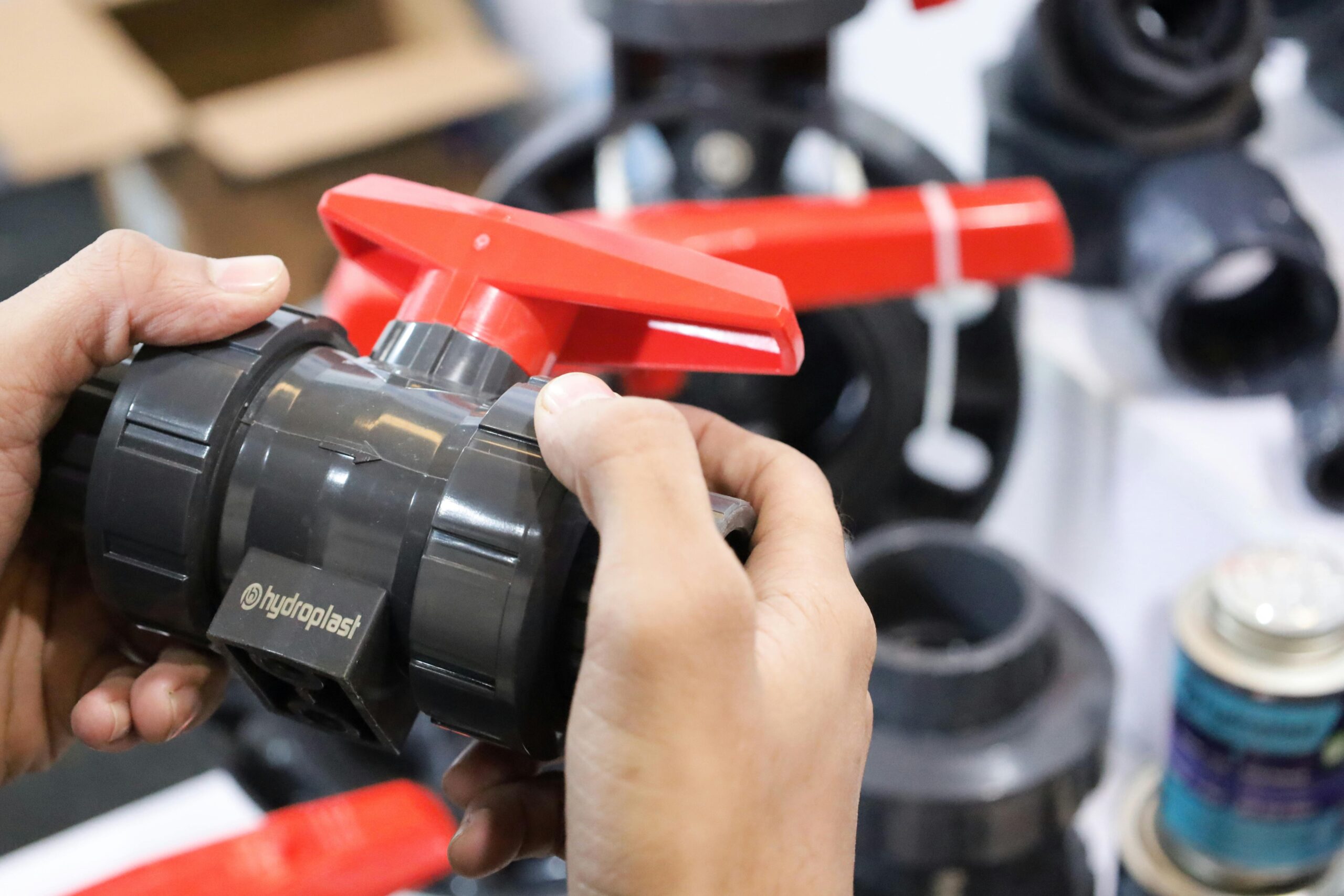 Close-up of hands examining a Hydroplast industrial valve at a trade expo.