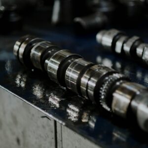 Detailed shot of a metal camshaft on a workbench, perfect for automotive industry themes.
