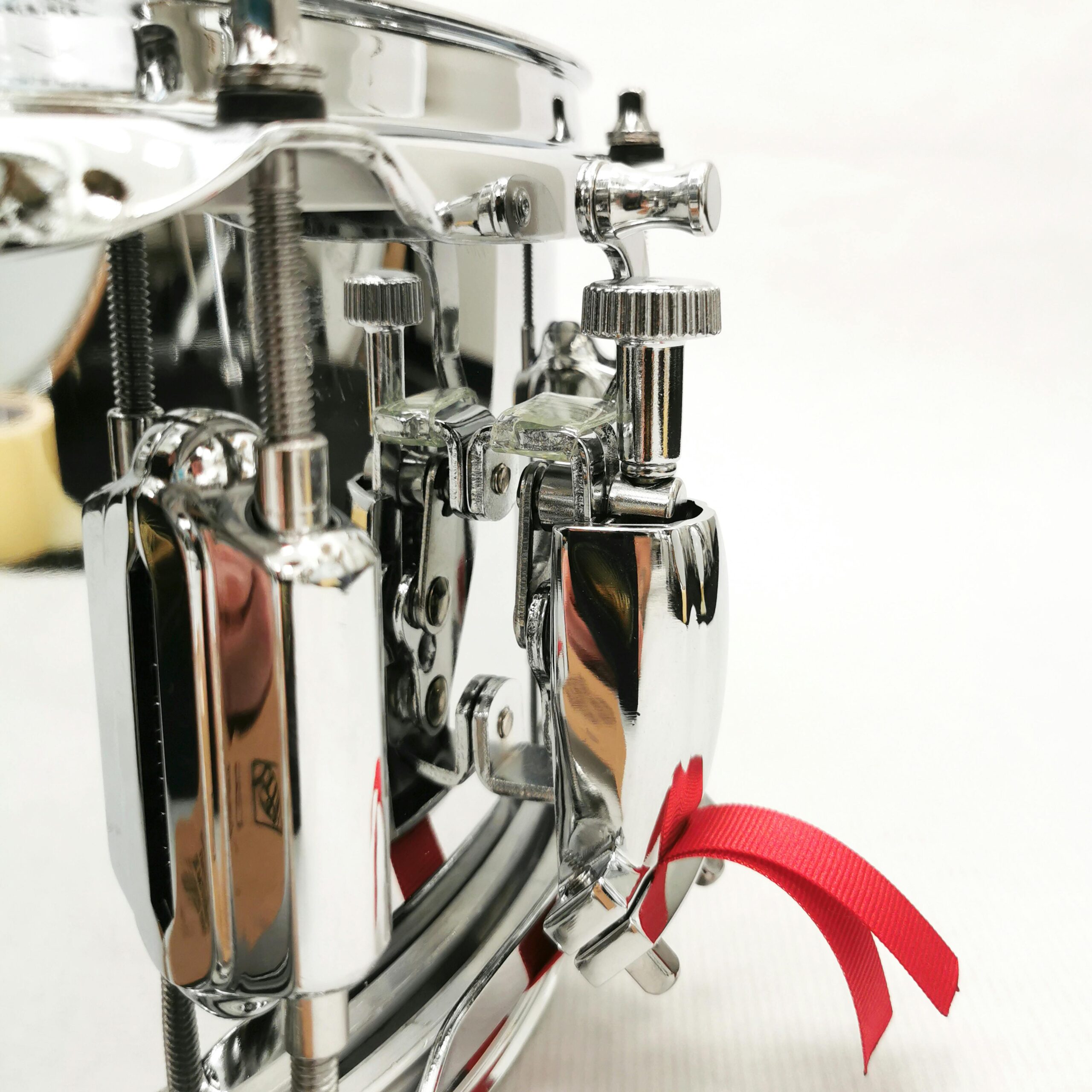 Detailed view of chrome drum hardware with a shiny finish and red ribbon accent.